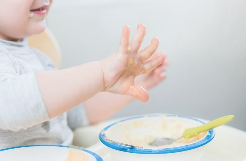 スプーンと手づかみで食事する子ども