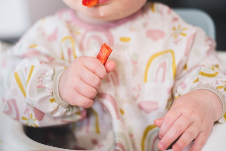 にんじんを手づかみ食べする赤ちゃん