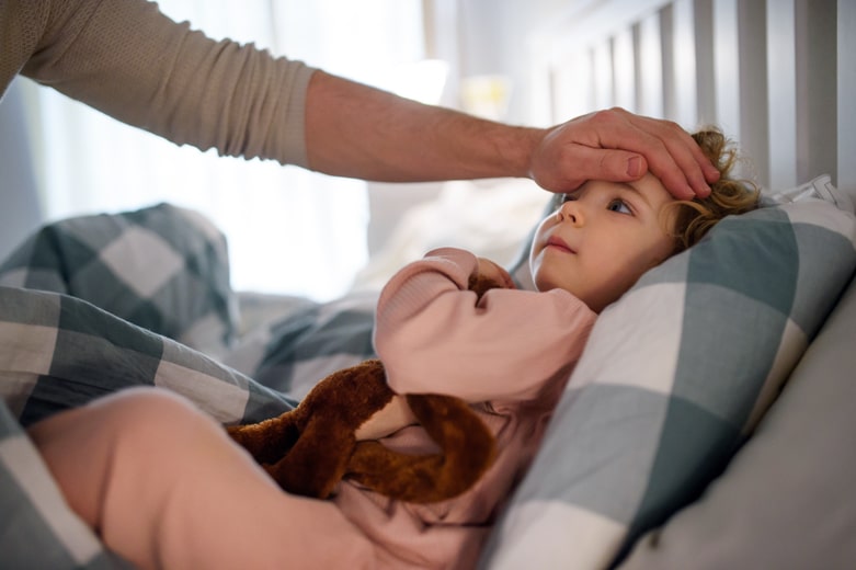 子どもの額に手を当てる母